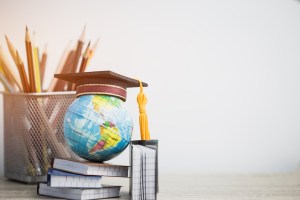 Concept of global business study abroad education. Graduation hat on models globe, books with pencils on wood white background. Congratulations to graduated, Studies lead to success. Back to School